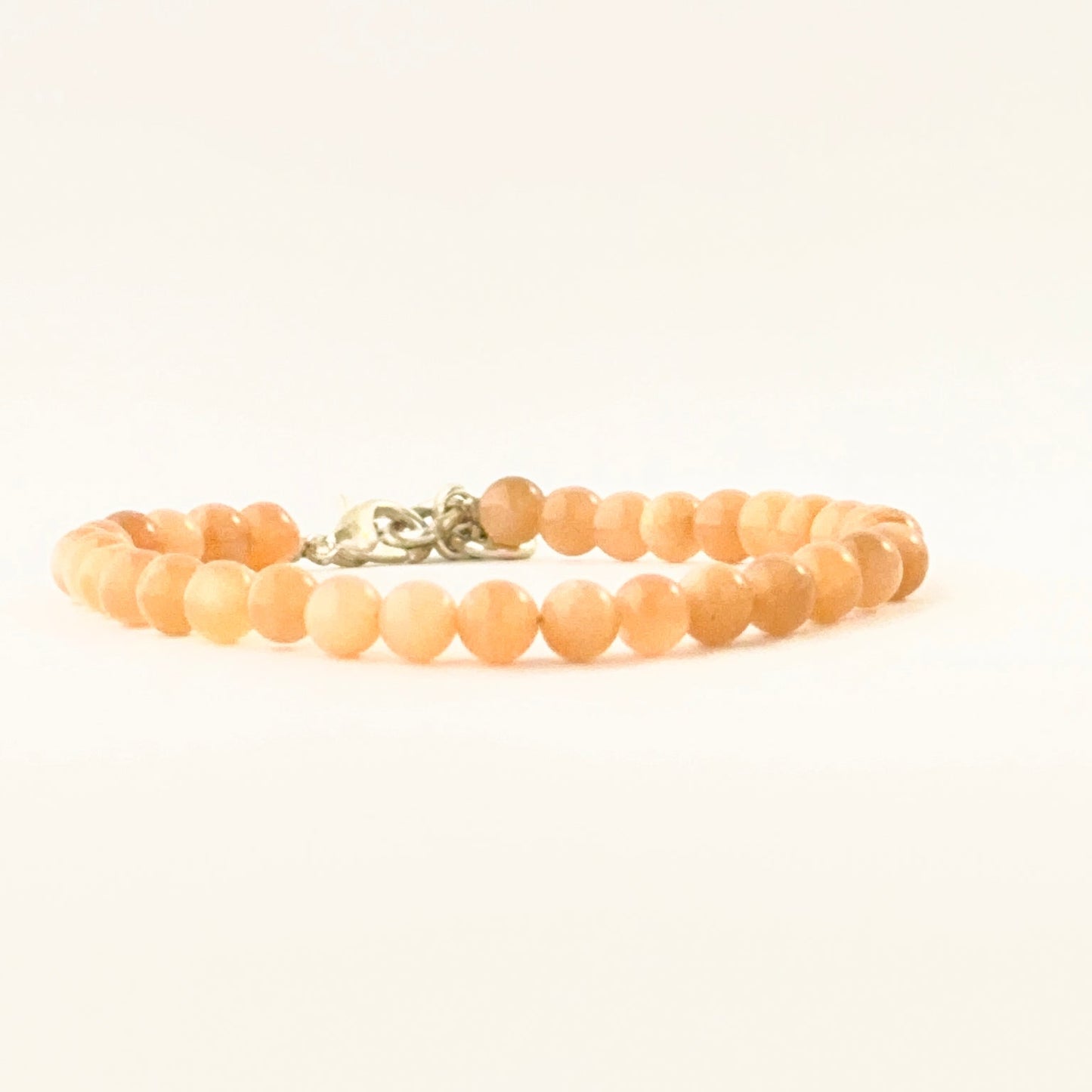 Single‑strand peach moonstone bracelet with adjustable closure.