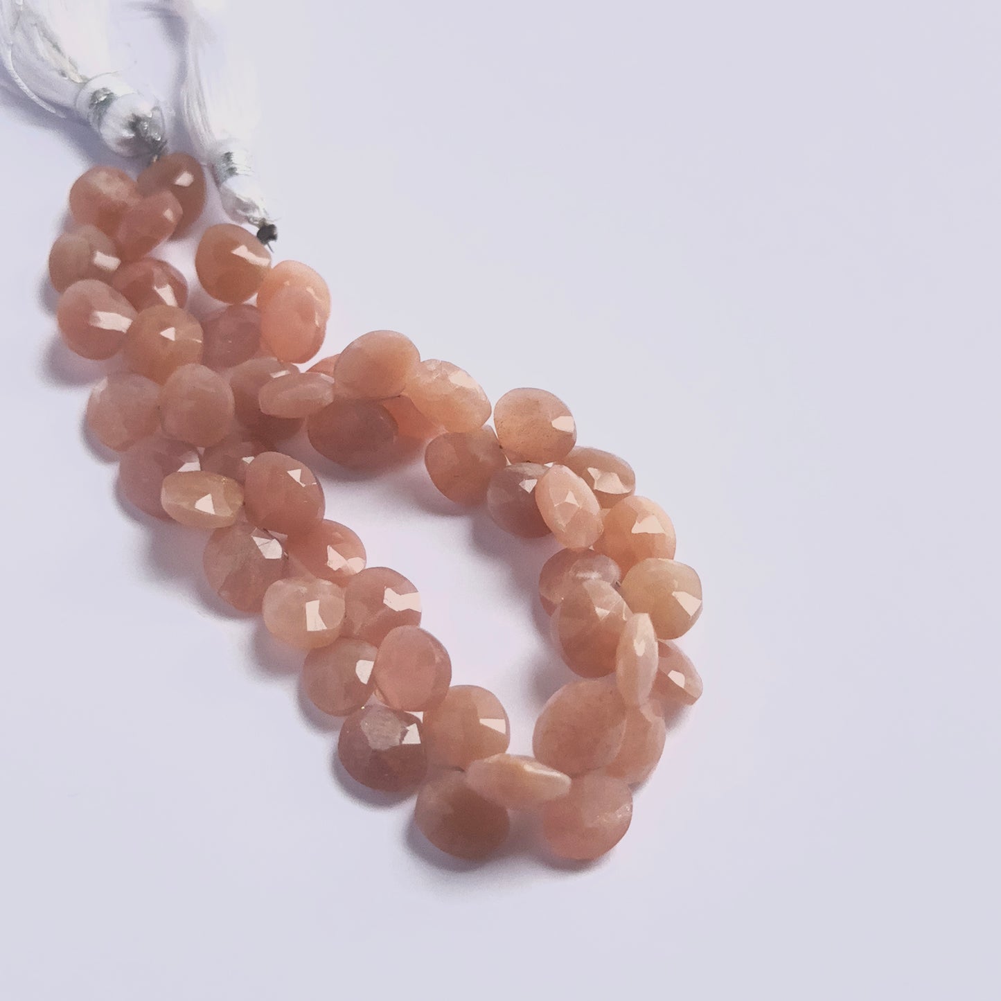 Stone beads in a strand of Peach Moonstone, highlighting their polished facets and consistent 9–9.5mm size.
