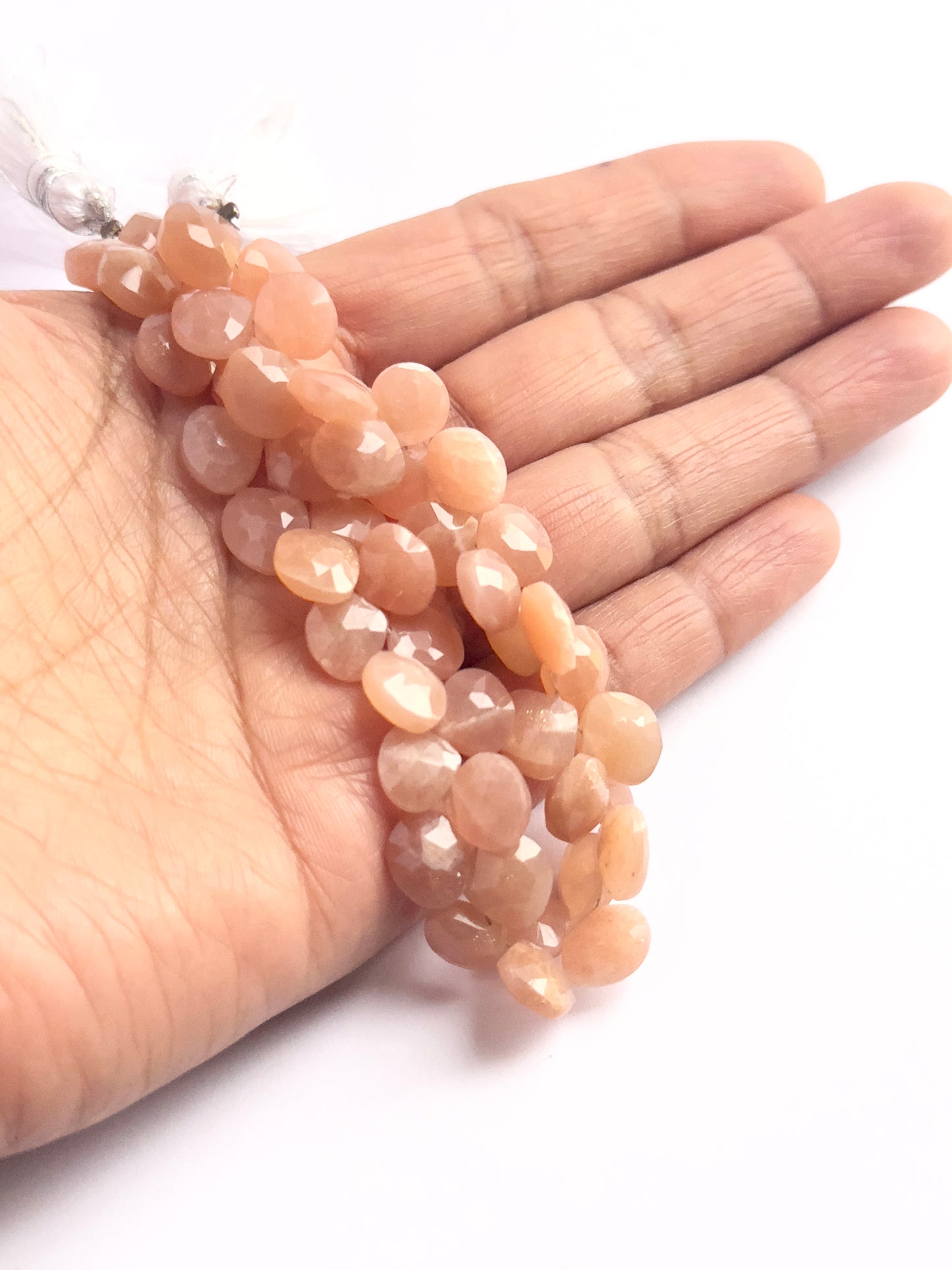 A dial gauge measures the Peach Moonstone faceted briolette 9–9.5mm gemstone.