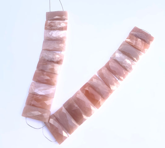 Peach Moonstone faceted rectangle gemstone beads arranged in a strand with soft peach tones.
