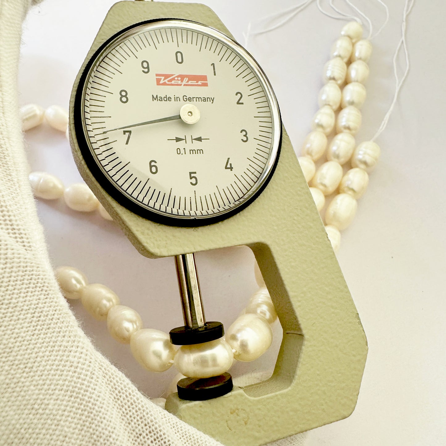 A dial gauge measures the pearl oval textured gemstone.