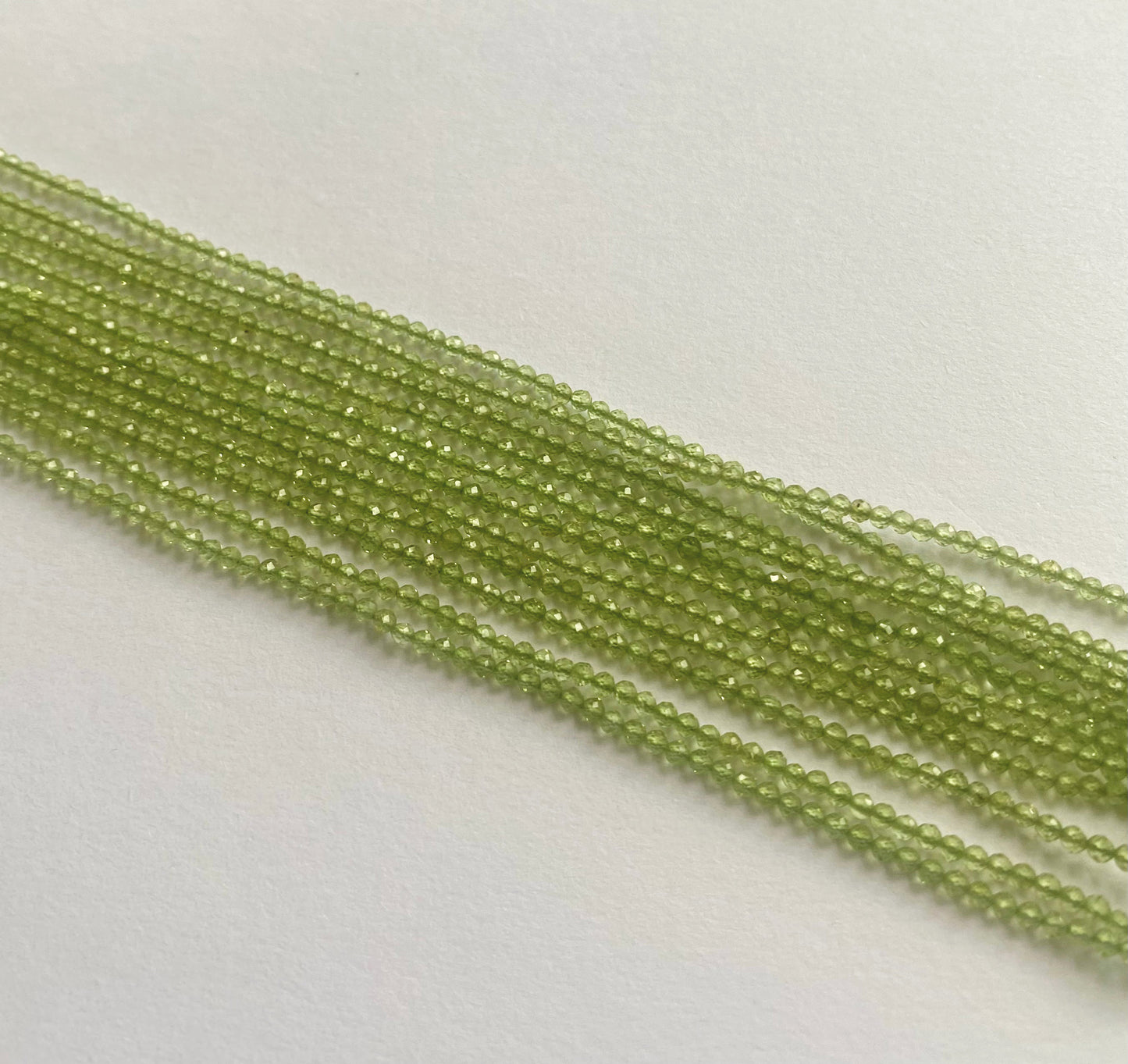 Peridot faceted rondelle beads in 1.9–2.2mm sizes, strung neatly on a 32cm strand with a brilliant green hue.