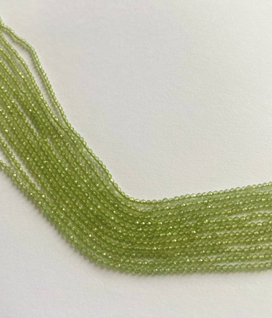 Macro shot of sparkling green Peridot gemstones with precision faceted rondelle cut.