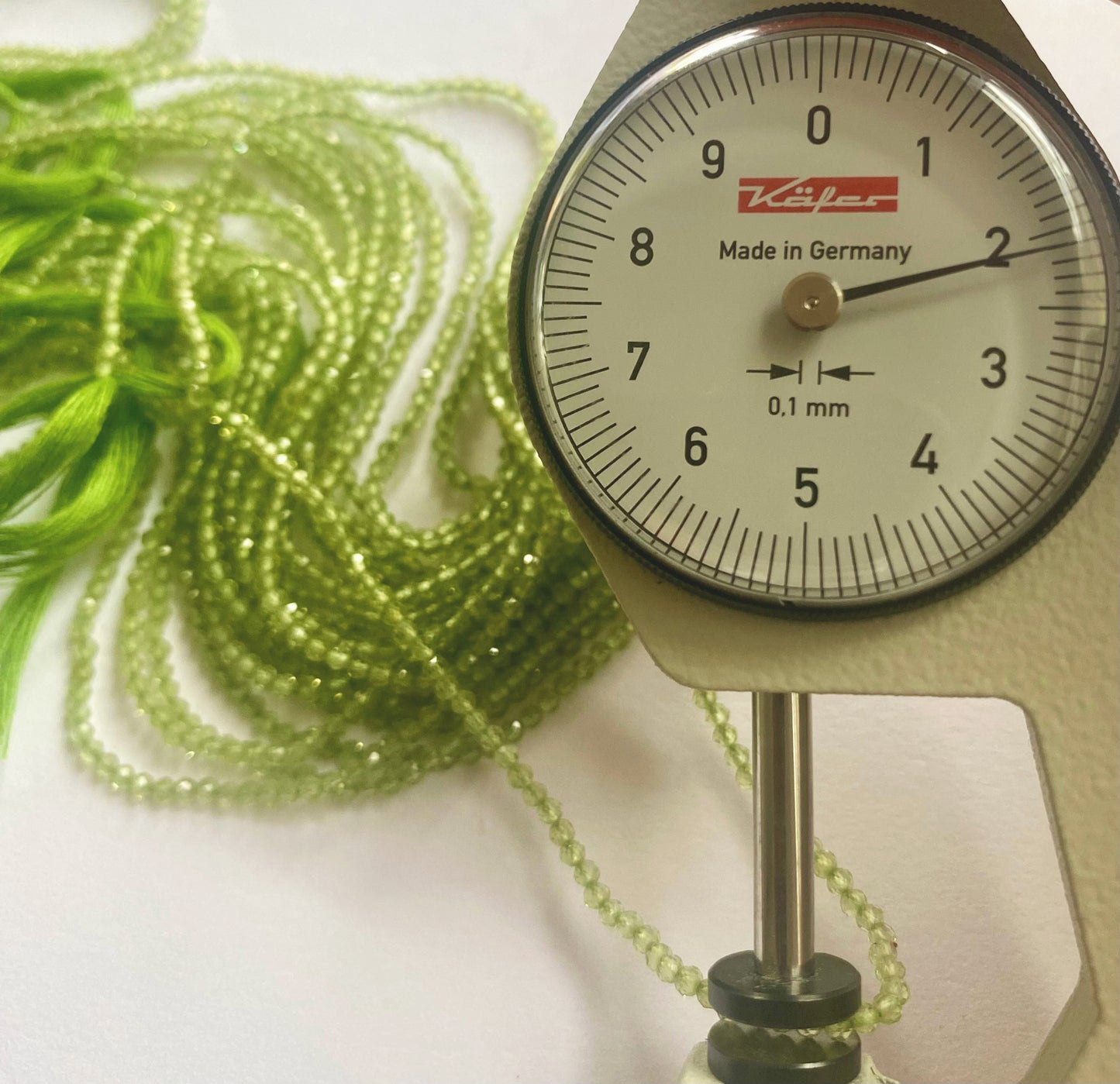 A dial gauge measures the Peridot faceted rondelle 2.2mm gemstone.