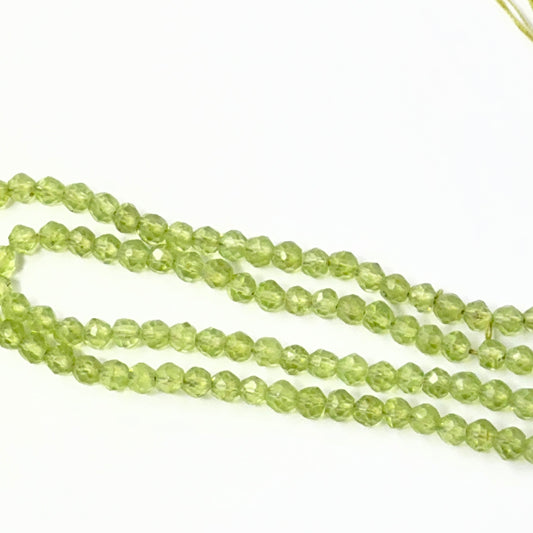 Close view of polished Peridot faceted rondelles arranged on a 15cm strand for handmade jewellery components.