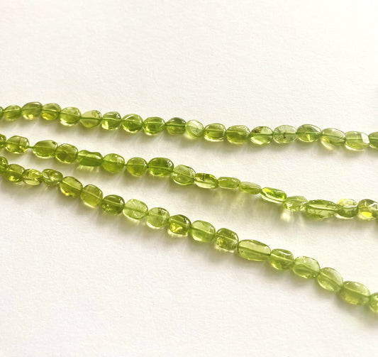Close-up of peridot gemstone beads showing their polished oval cut and natural clarity.