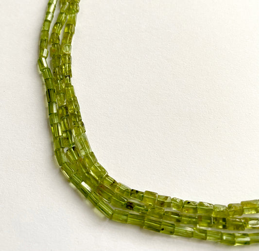 Close-up of tube-shaped Peridot gemstones with a smooth surface and polished finish.