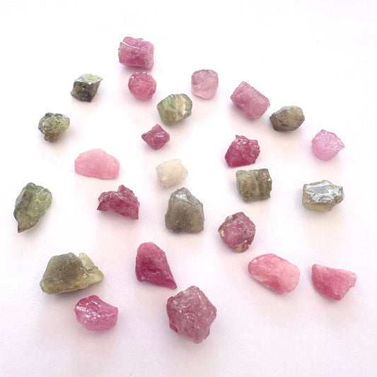 Pink and green sapphire rough stones arranged to highlight their vibrant colour and natural texture.