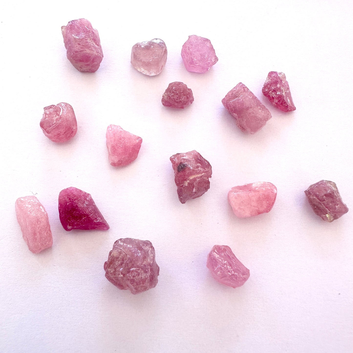 Mixed sapphires with vivid hues and rough cuts displayed on a neutral background.