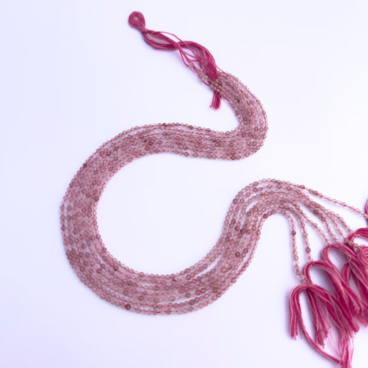 Natural Strawberry Quartz stone beads arranged in strands with shimmering inclusions.