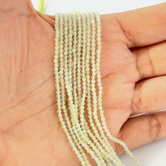 A hand holds light green Prehnite faceted rondelle gemstone strand, 2.2mm bead size.