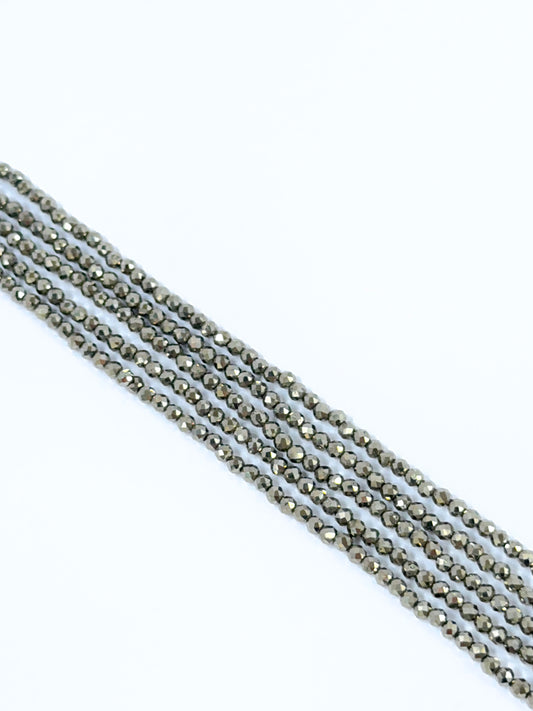 Close‑up of Pyrite stone beads arranged in a strand with reflective surfaces.
