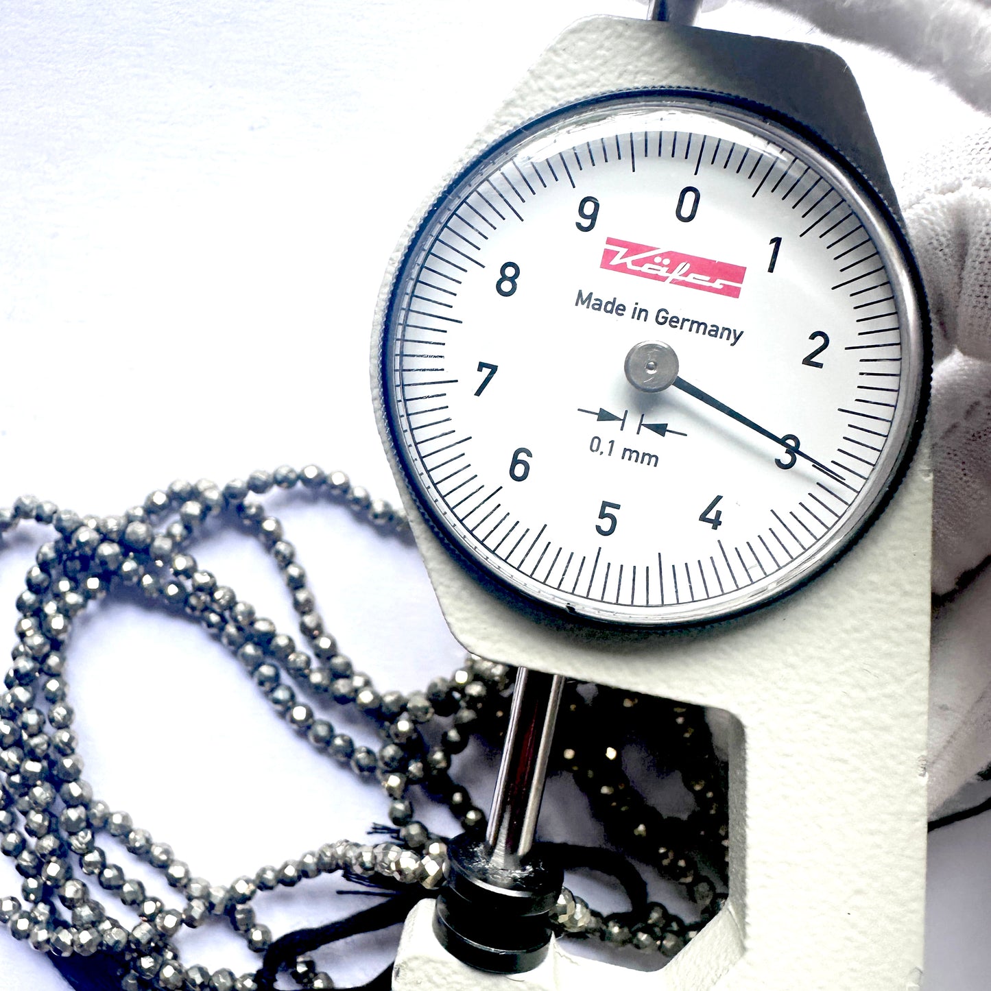 A dial gauge measures the pyrite faceted rondelle 3mm gemstone.