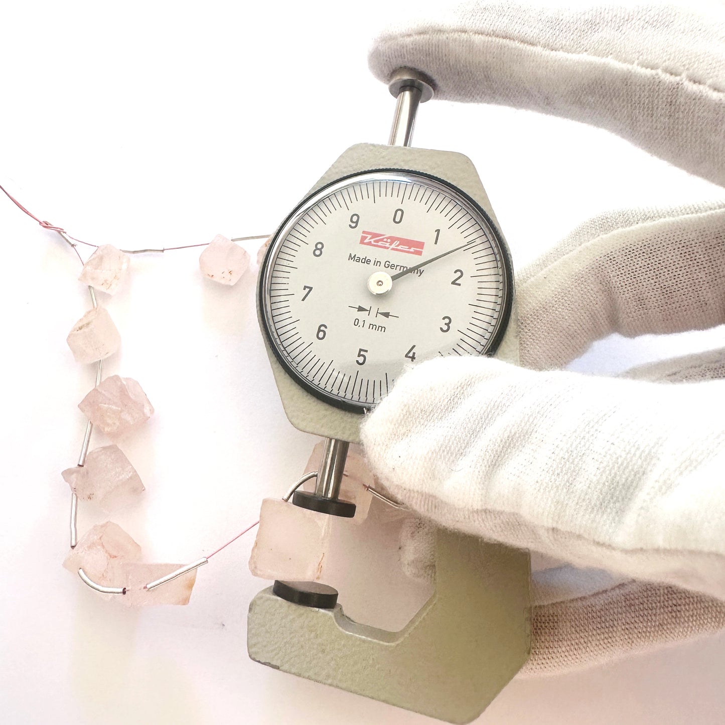 A dial gauge measures the Quartz rough cut 10mm gemstone.
