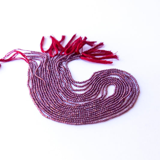 Genuine Rhodolite Garnet gemstone beads displaying rich raspberry tones, polished facets, and a neatly arranged strand for jewellery design.