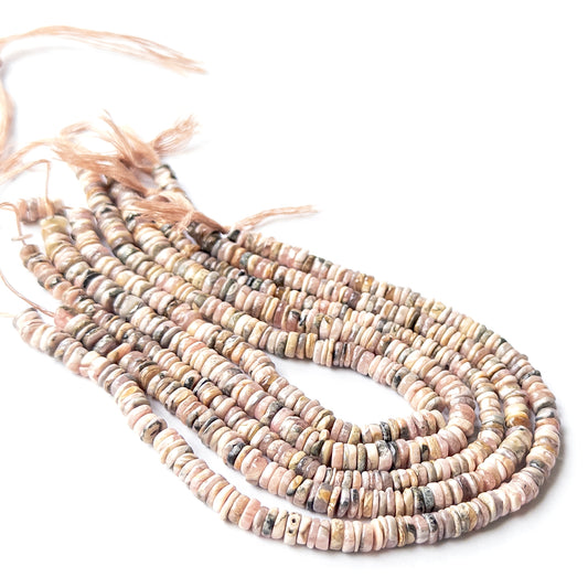 Close‑up of genuine Rhodonite wheel heishi stone beads with clean shaping and warm pink colour.