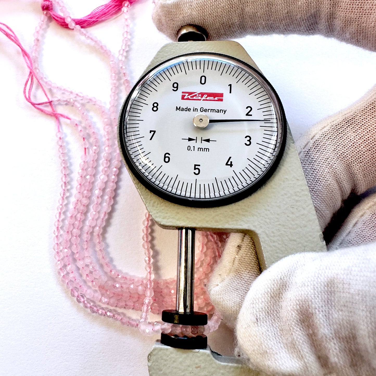 A dial gauge measures the Rose Quartz faceted rondelle 2.4mm gemstone.