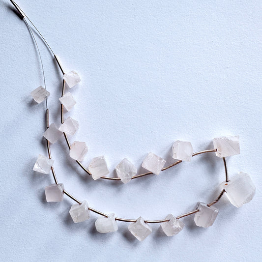 Assorted Rose Quartz gemstones arranged in a strand, highlighting their semi-polished finish and varied bead sizes.