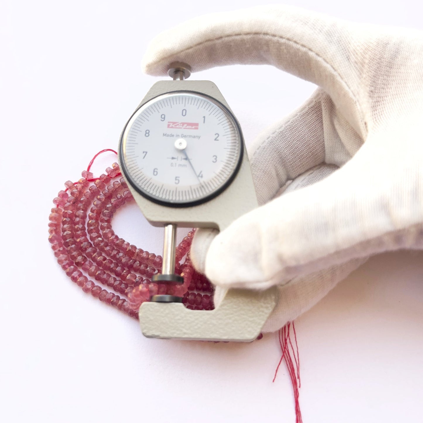A dial gauge measures the ruby faceted rondelle 4.2–4.5mm gemstone.