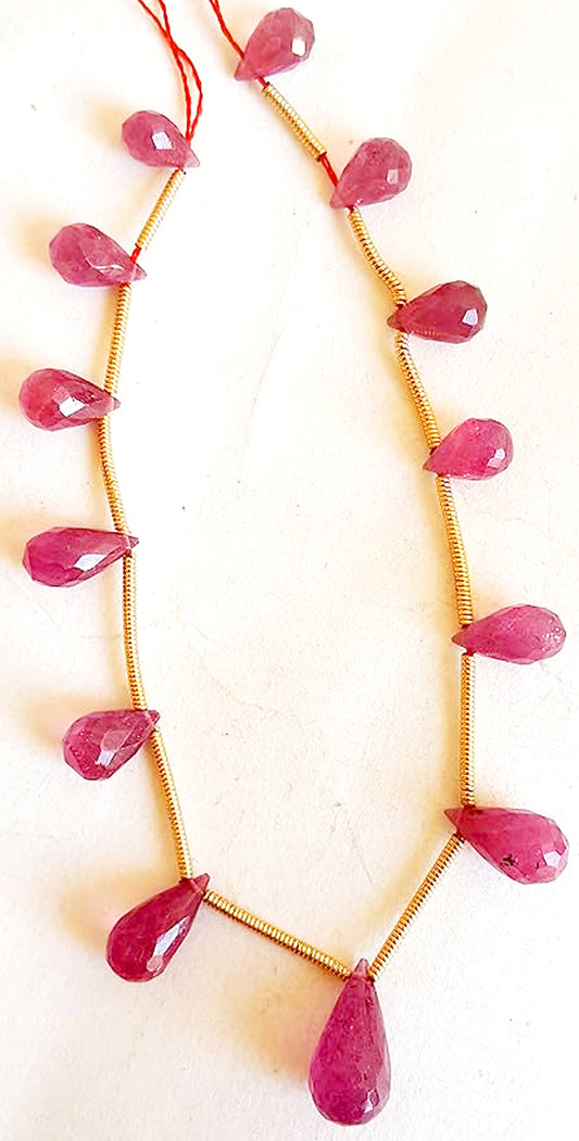 Glimmering ruby faceted beads laid out in a neat strand arrangement with intense red shine.