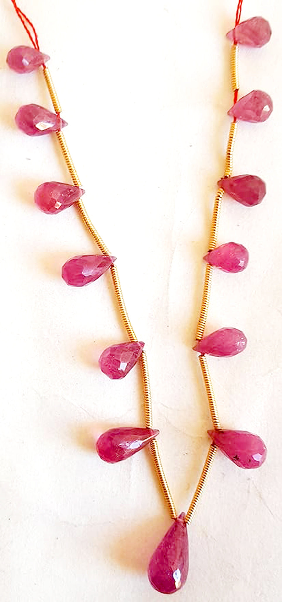 Mixed-size ruby teardrops glistening under soft light, revealing expert cut and clarity.