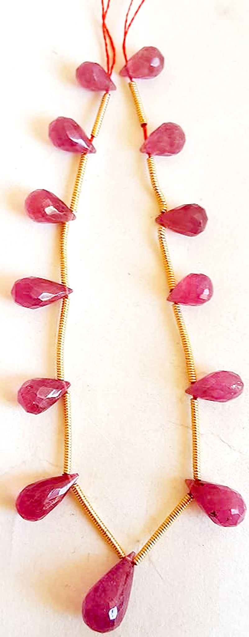 Close-up of ruby gemstone beads featuring faceted teardrop cut and vivid crimson hues.