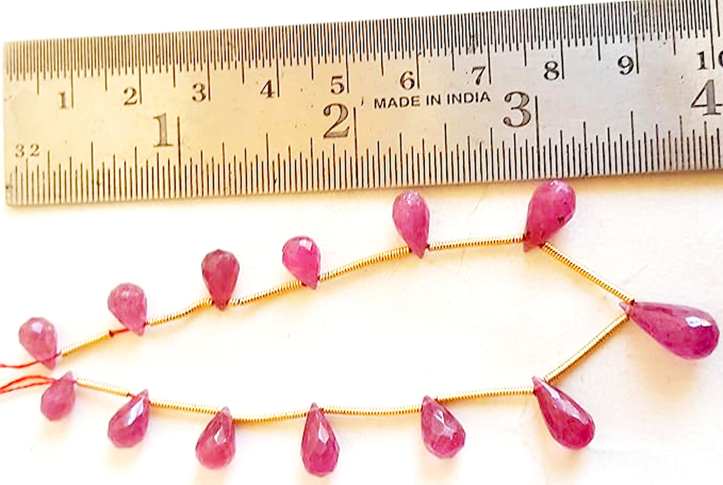 A rulers measures the ruby teardrop gemstone.