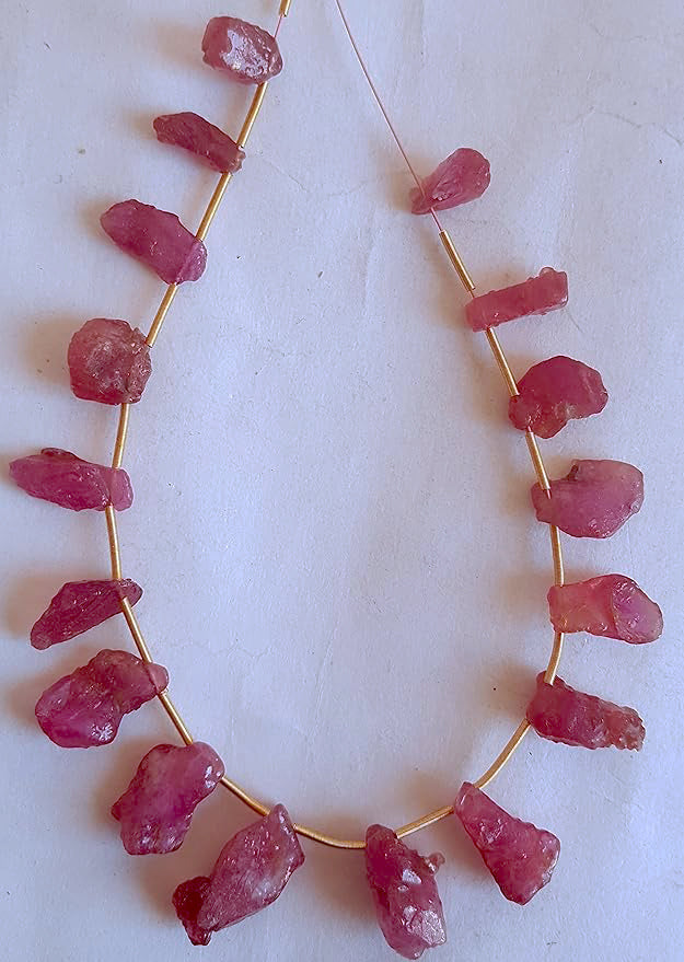 Assorted ruby beads with uneven cuts and matte finish arranged in a loose strand.