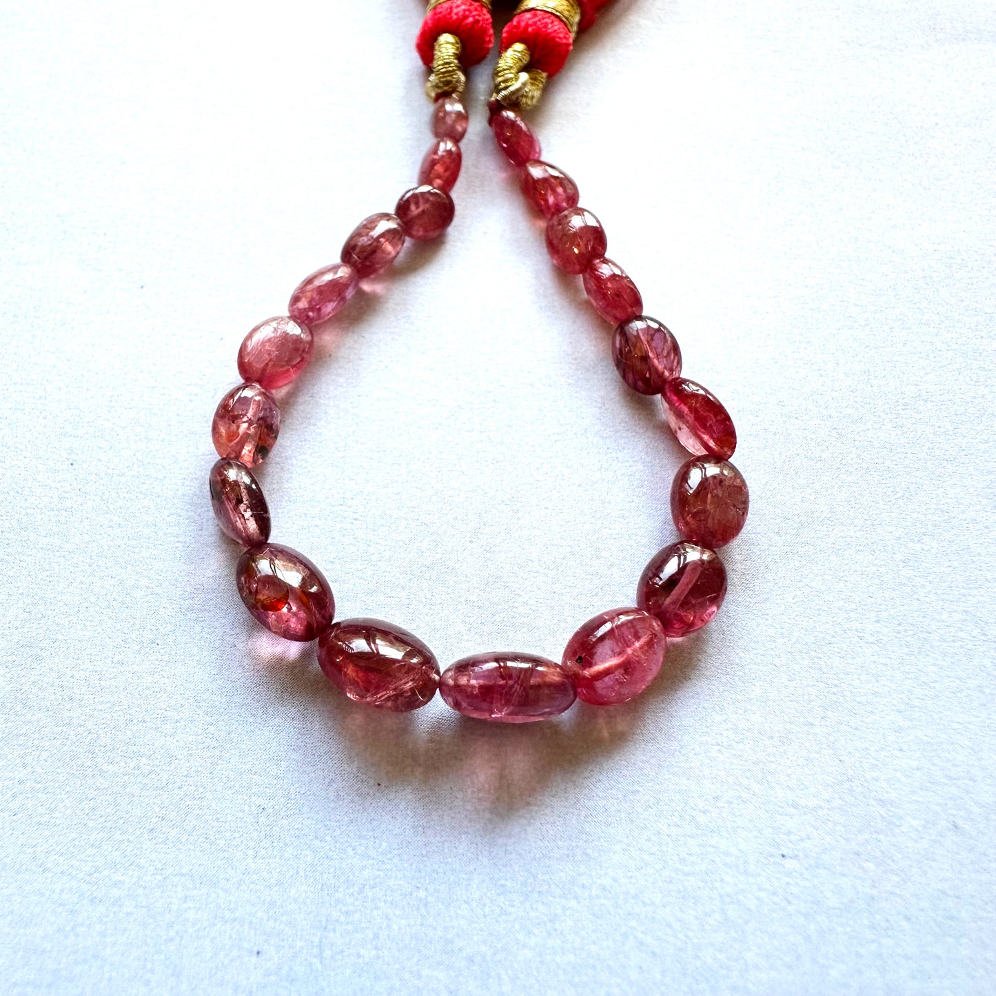 Close-up of Ruby gemstone beads with high-polish finish on smooth oval surfaces