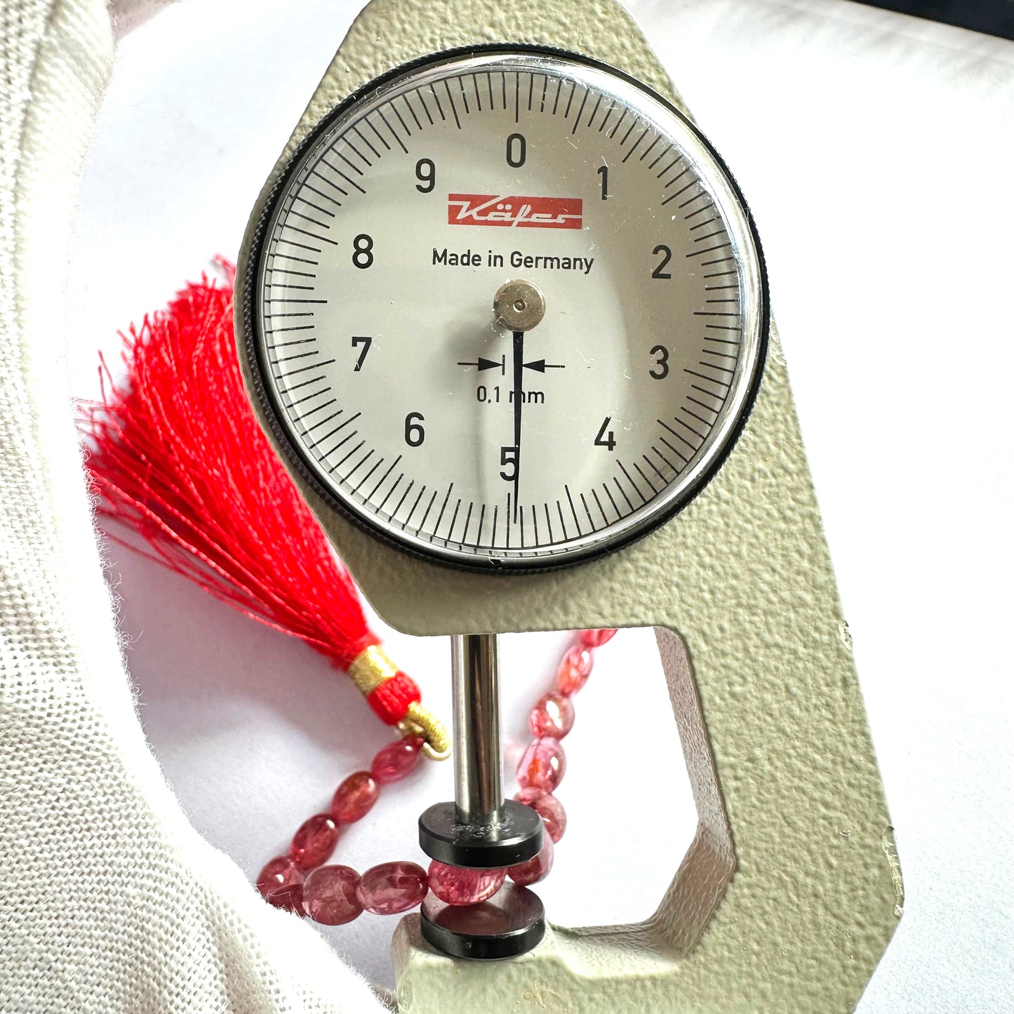 A dial gauge measures the Ruby smooth oval gemstone.