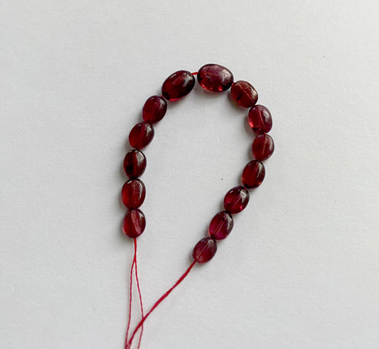 Close-up of ruby gemstone beads showing their smooth oval cut and rich crimson colour.