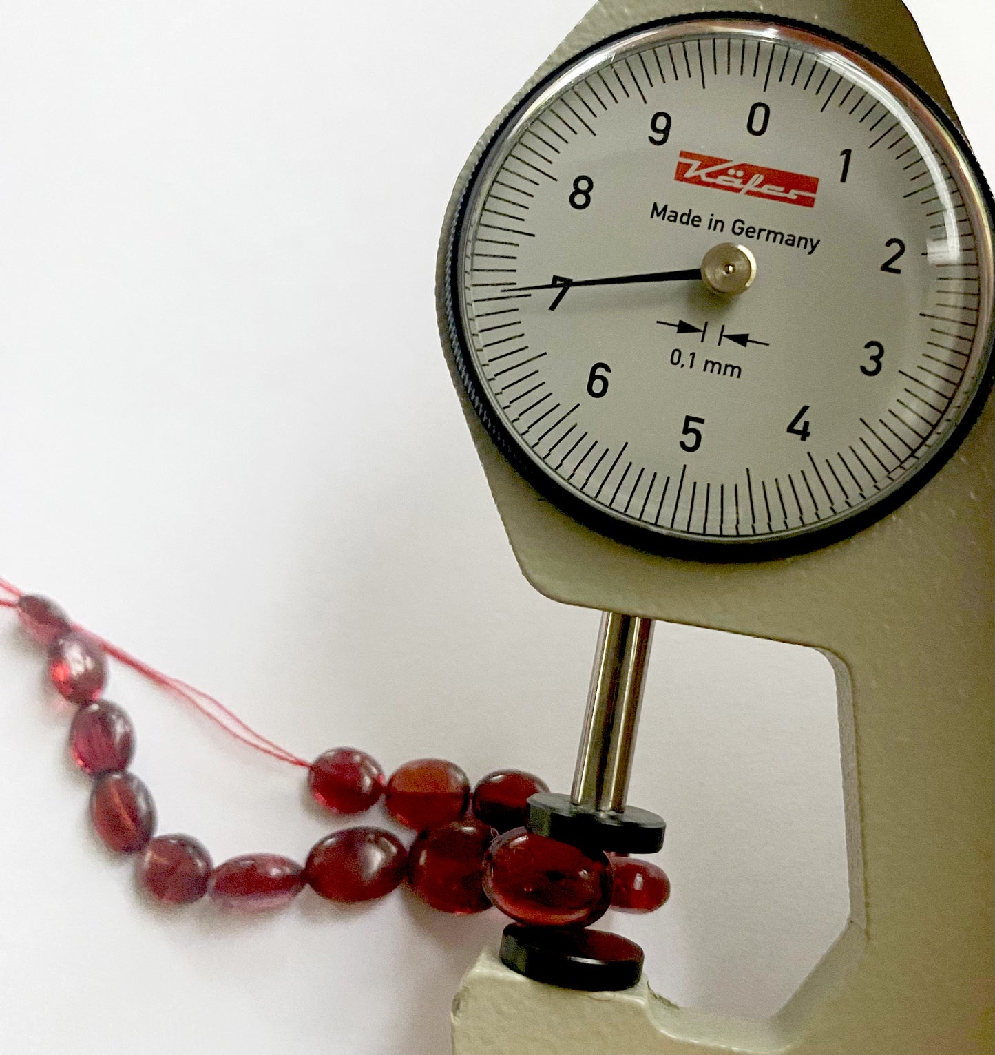 A dial gauge measures the ruby smooth oval 5.5m–7.5mm gemstone.