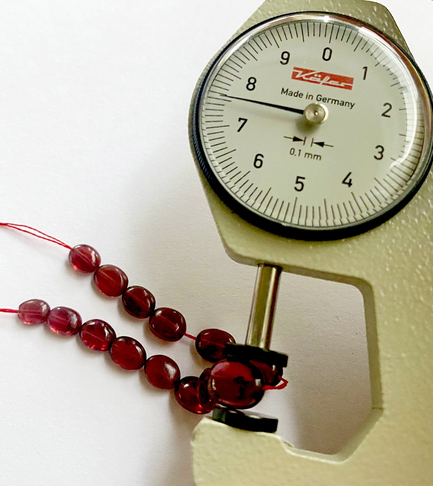 A dial gauge measures the ruby smooth oval 5.5m–7.5mm gemstone.