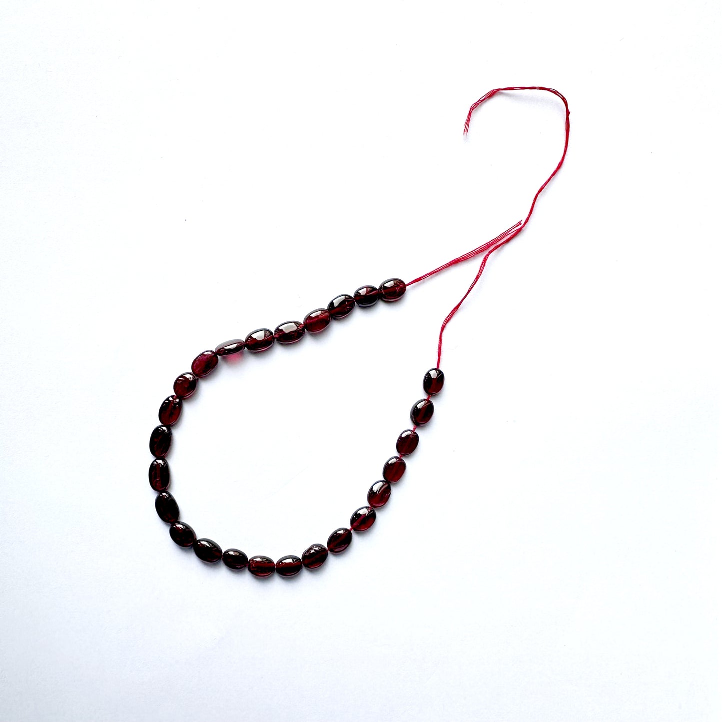 Ruby beads with consistent oval shape and radiant clarity across 26 pieces.