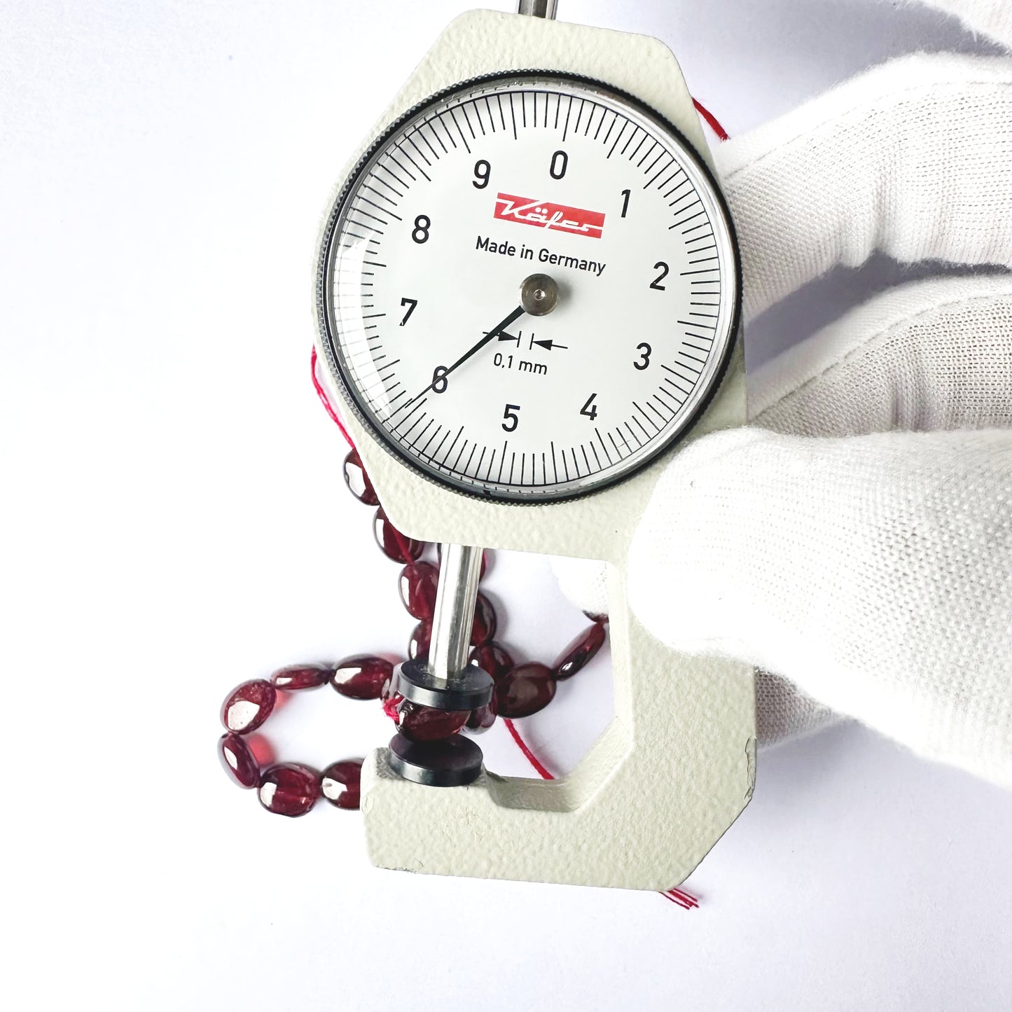 A dial gauge measures the Ruby smooth oval 7.5–8.5mm x 6mm gemstone.