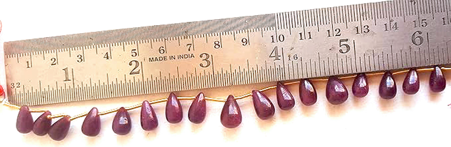 A ruler measures the ruby smooth teardrop gemstone for precision and quality control.