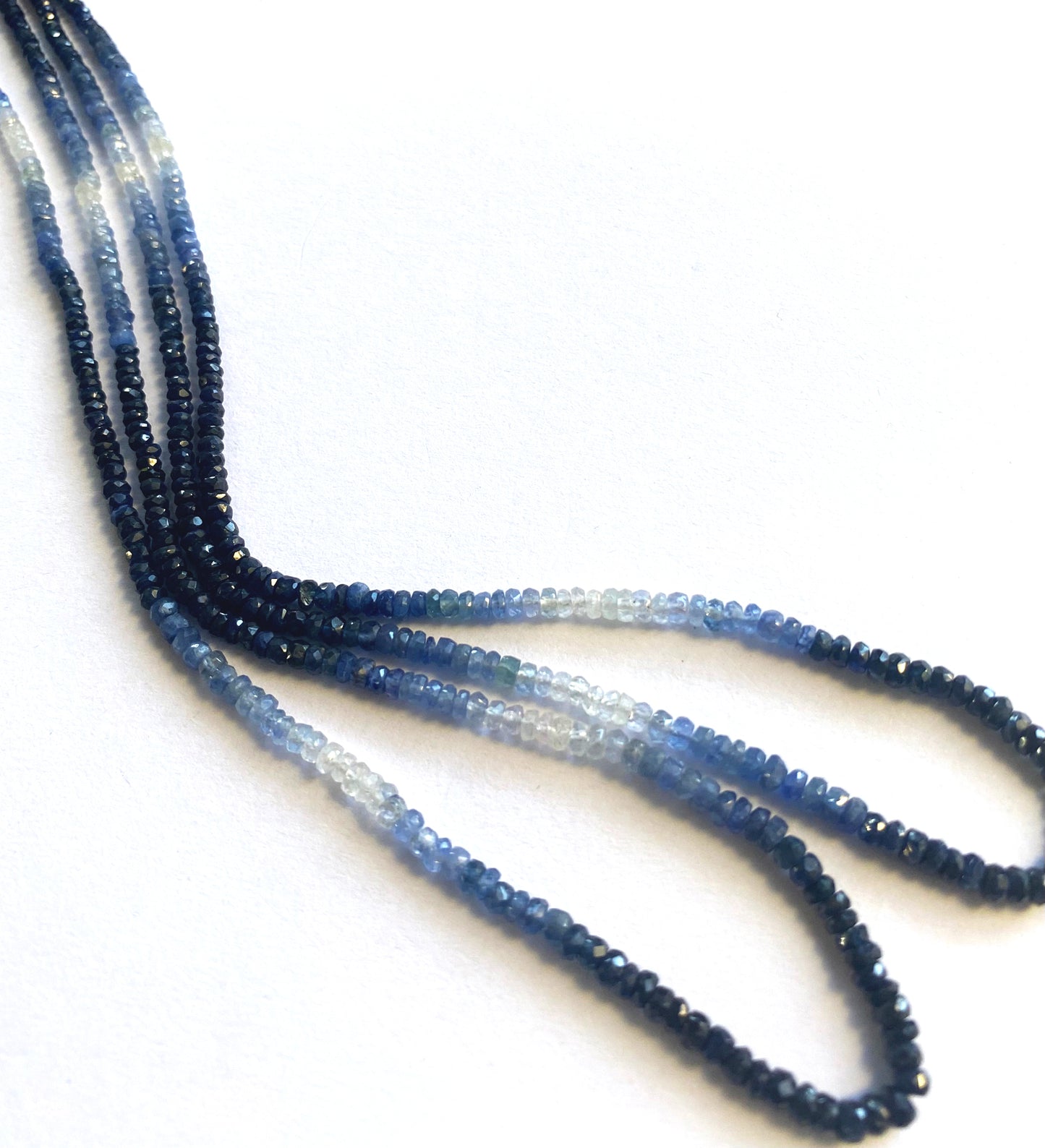Gradient sapphire rondelle gemstones with high clarity and polished finish in cool blue hues.