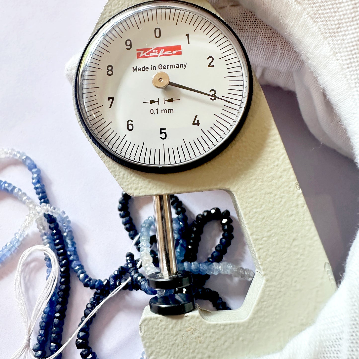 A dial gauge measures the sapphire rondelle 2.9–3.9mm gemstone.