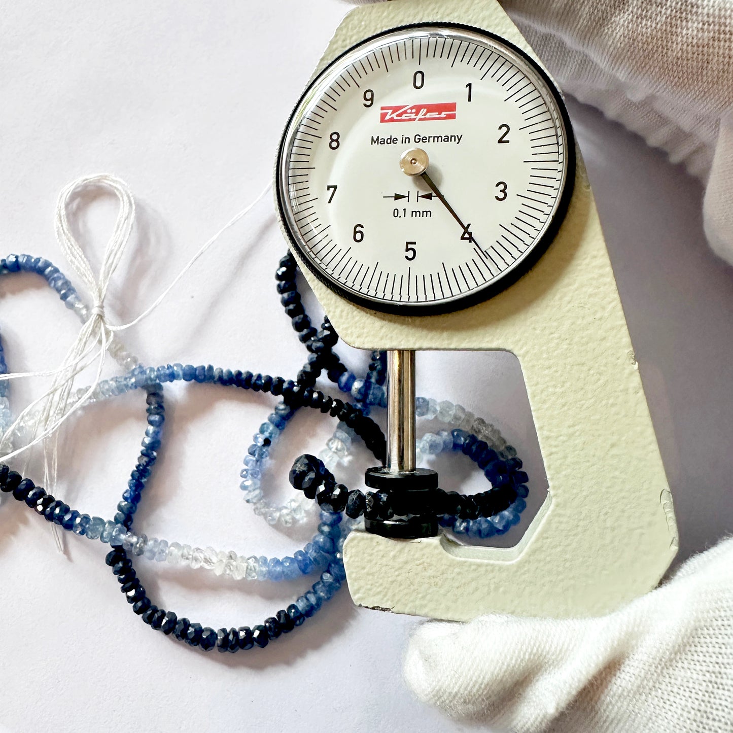 A dial gauge measures the sapphire rondelle 2.9–3.9mm gemstone.