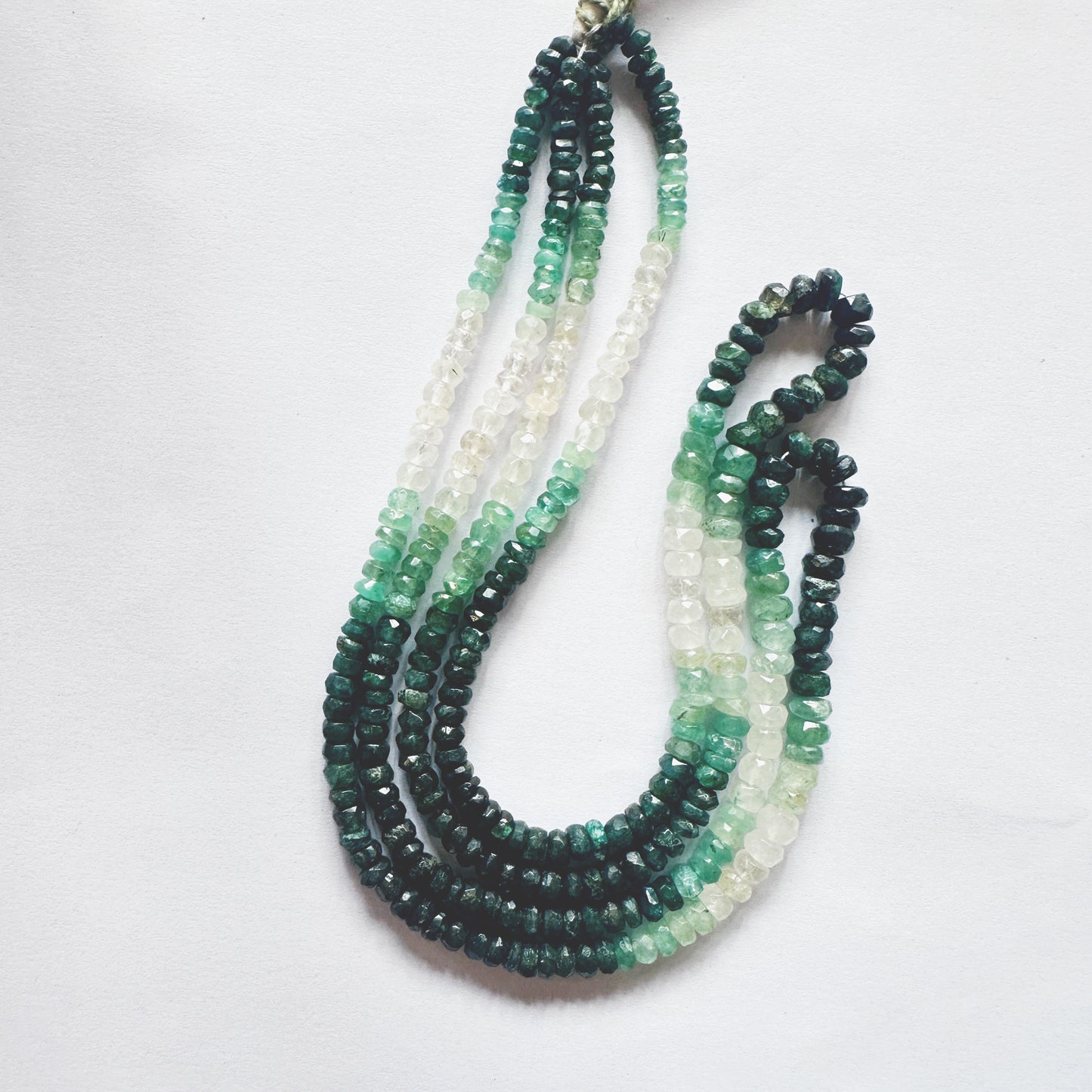 41cm strand of faceted Emerald beads arranged by size, exhibiting deep green brilliance.