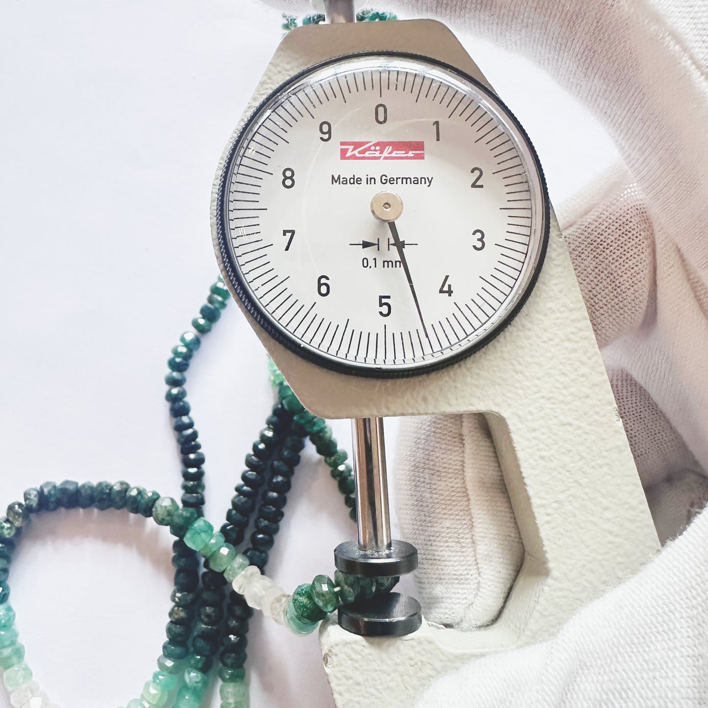 A dial gauge measures the Emerald faceted rondelle 3.6-5mm gemstone.