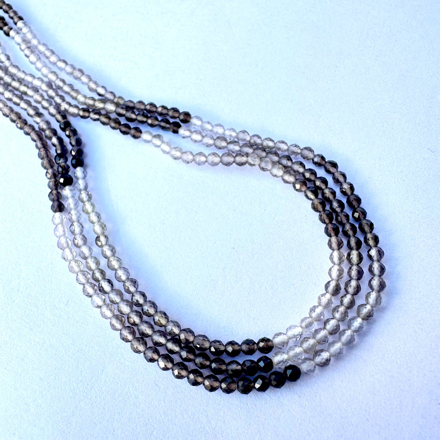 Close-up of smoky quartz beads showing shaded tones and sparkling faceted surfaces.