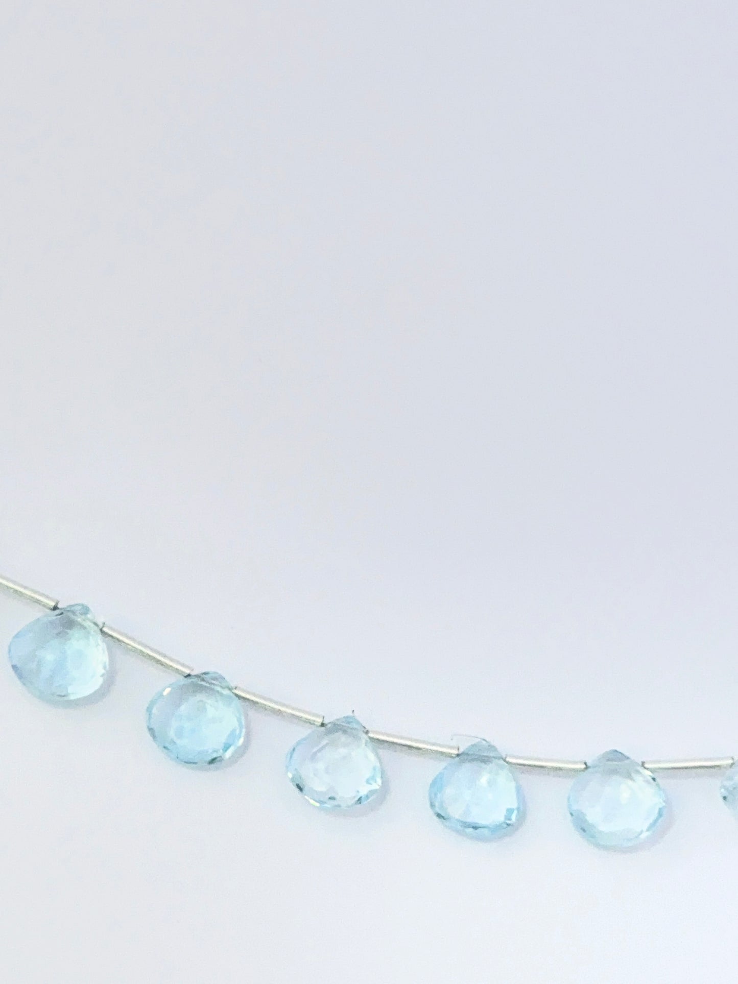 Stone beads made from Sky Blue Topaz showing polished briolette shapes and clear brilliance.