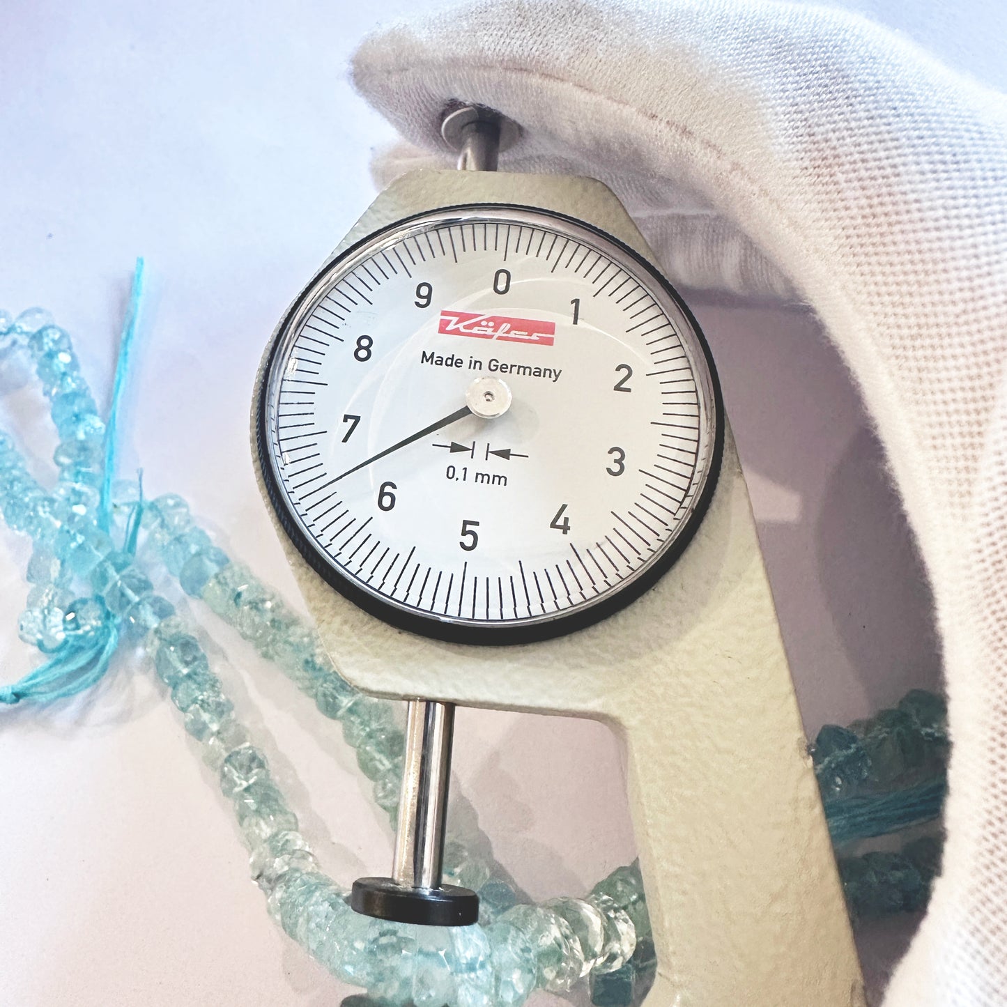A dial gauge measures the Topaz faceted rondelle gemstone.