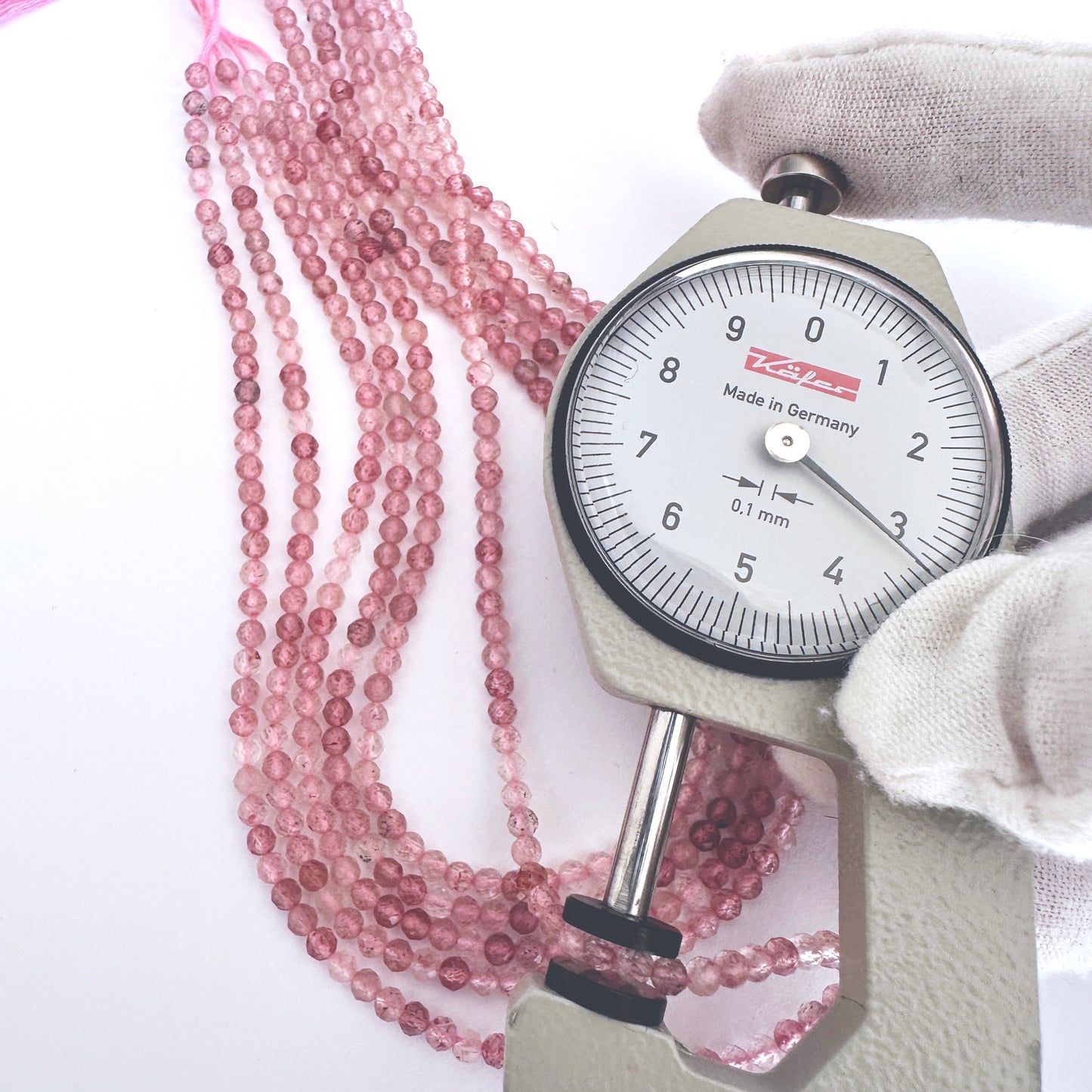 A dial gauge measures the Strawberry Quartz faceted rondelle 3.2mm gemstone.