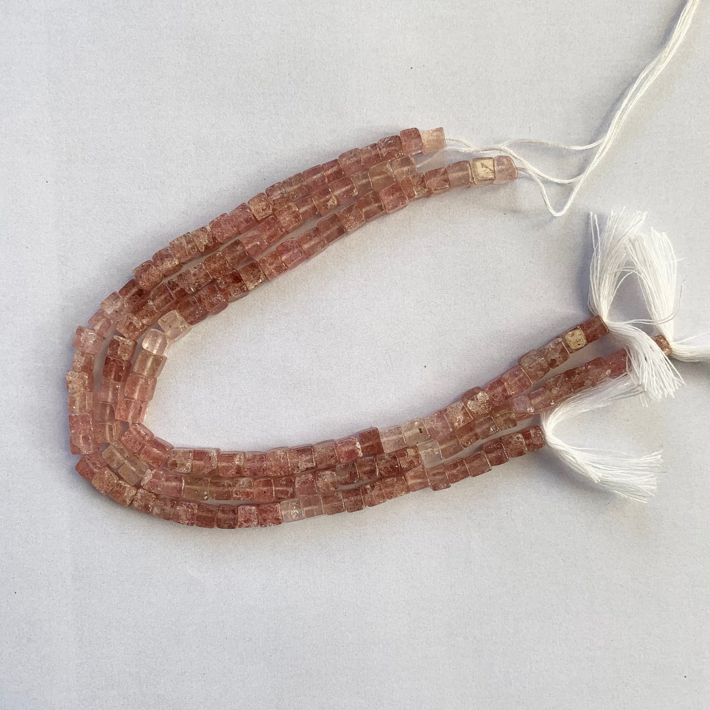 Gemstone strand featuring Strawberry Quartz cubes with delicate pink hues and smooth surfaces.