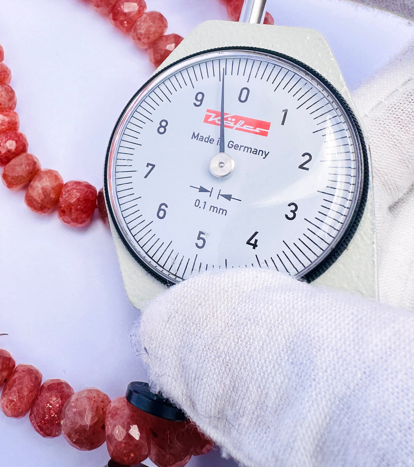 A dial gauge measures the Sunstone faceted rondelle 7–9mm gemstone.