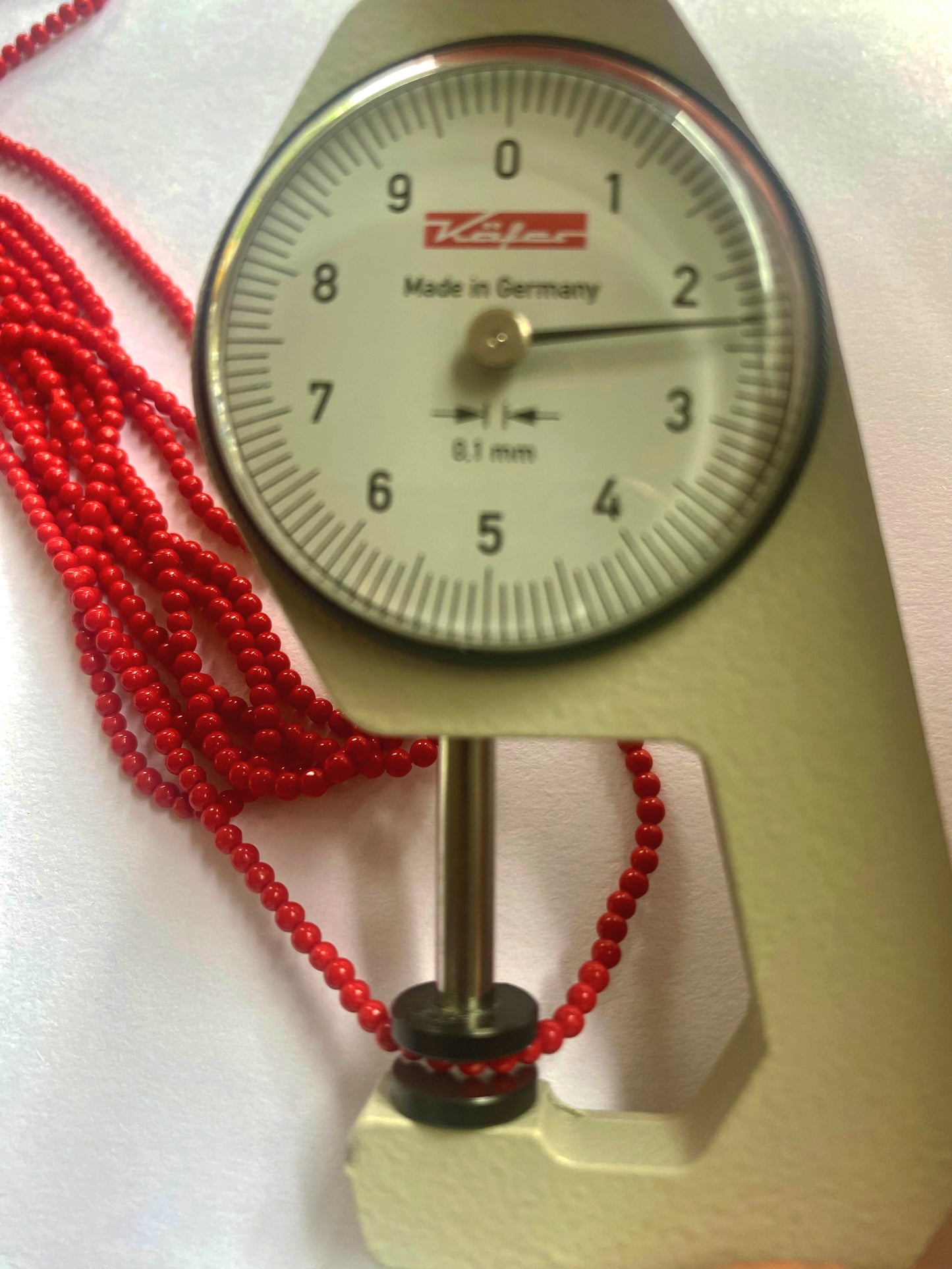 A person holds delicate strands of Taiwan Coral beads, showcasing their smooth design.