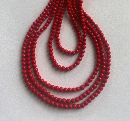 Close-up of polished 2.3mm Taiwan Coral beads showcasing vibrant colour and uniform spherical shape.