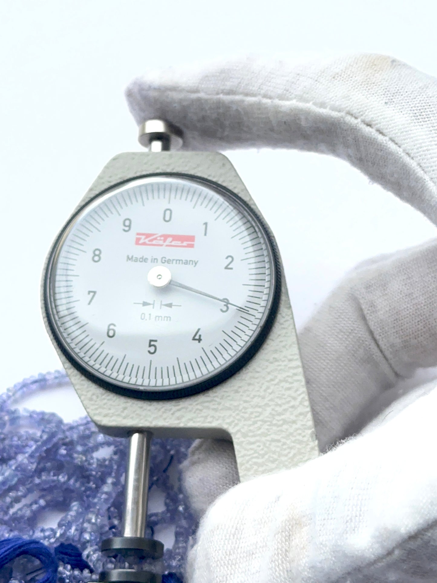 A dial gauge measures the tanzanite faceted rondelle 2.5–2.8mm gemstone.